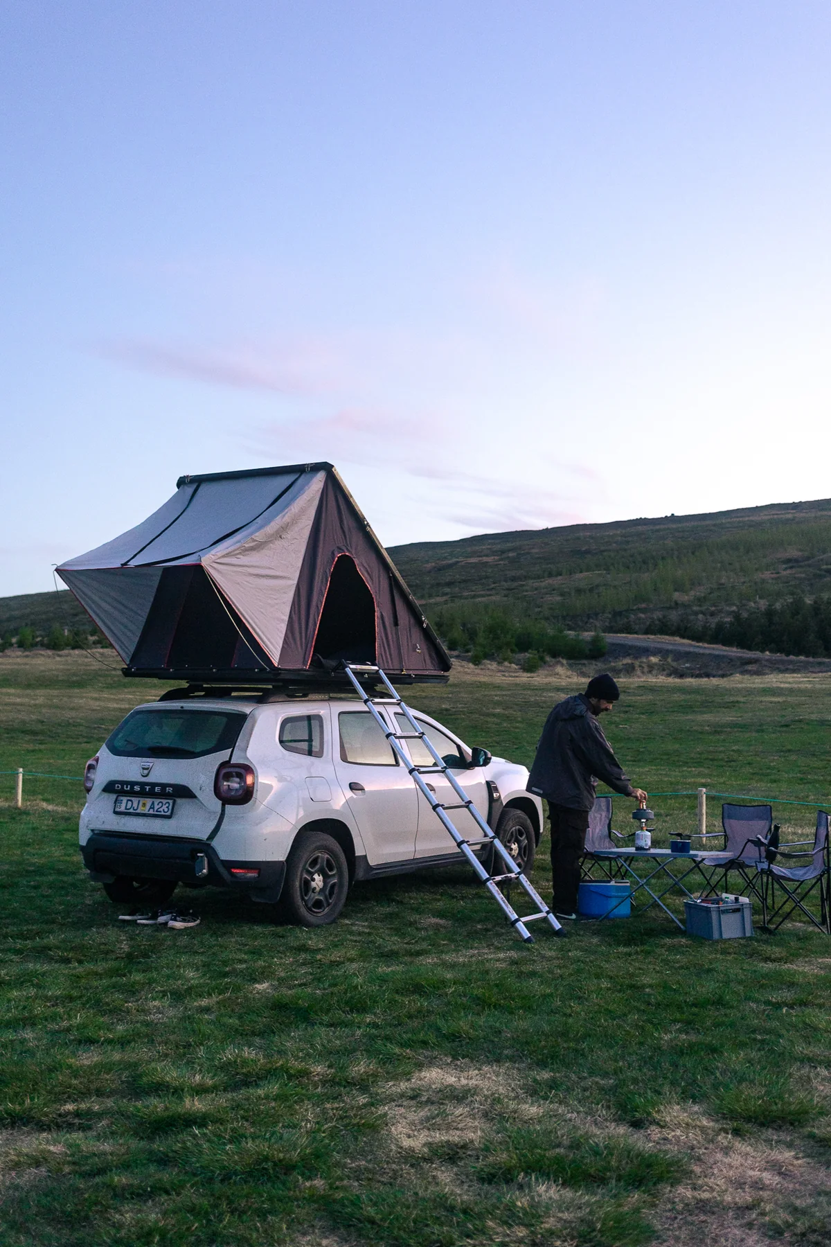Weißer Dacia Duster 4x4 mit geöffnetem Dachzelt auf einem Campingplatz in Island