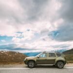 Aurlandsfjellet Norway. Car SUV Parked near Aurlandsfjellet Scenic Route Road in Summer Norwegian Landscape. Natural Norwegian Landmark and Popular Destination